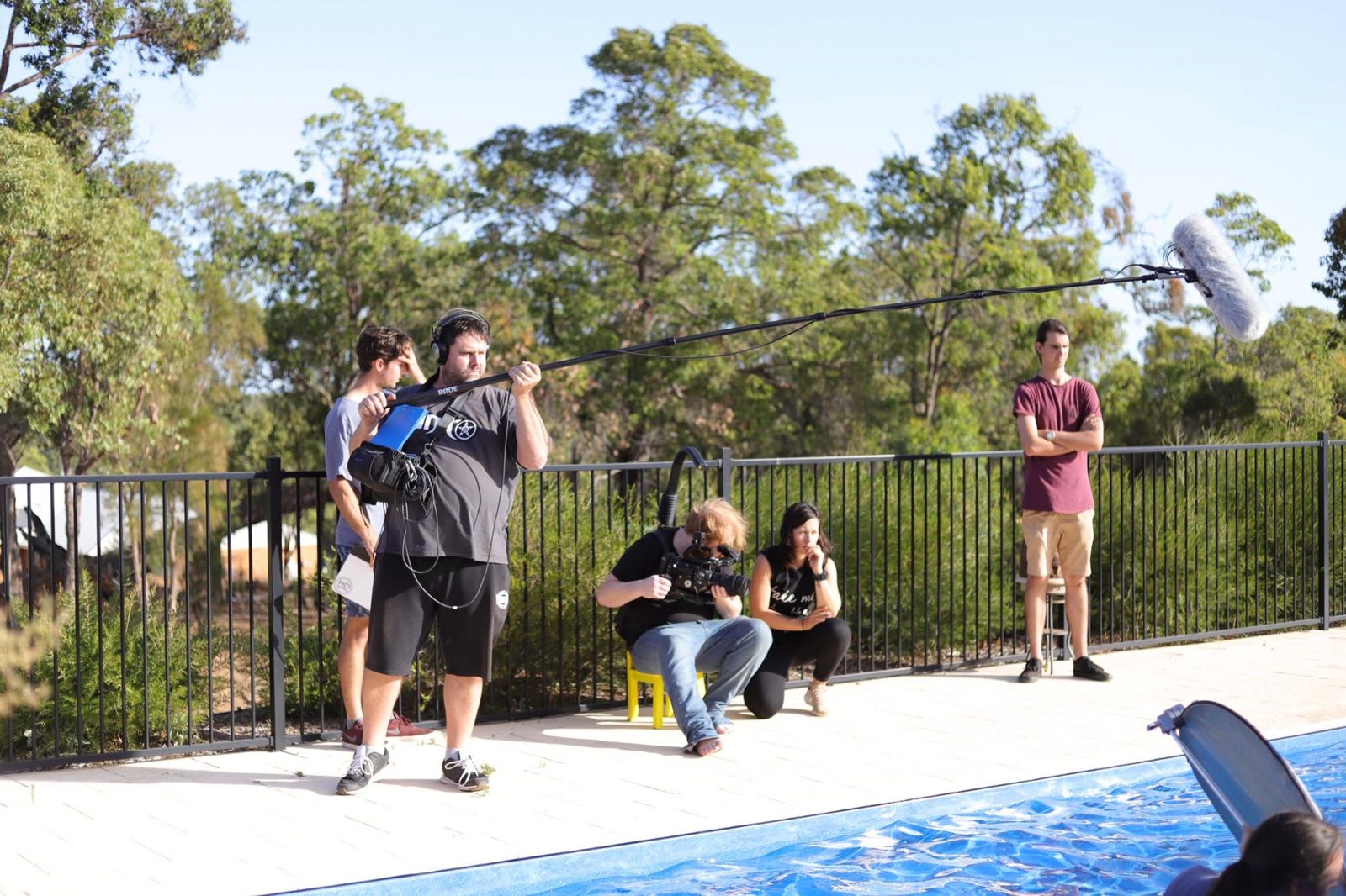 Kelly watching a take poolside with the camera and sound crew